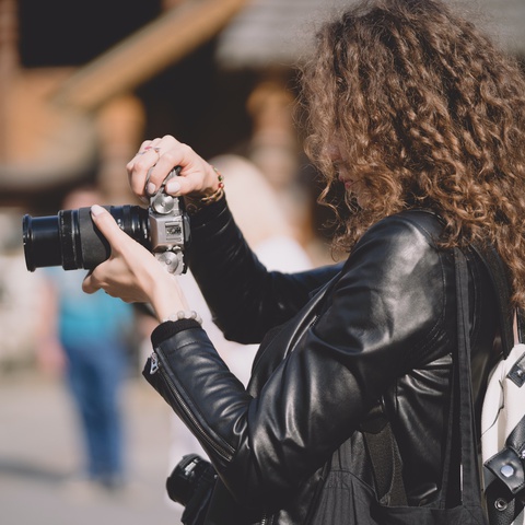 A woman takes a photo on a street