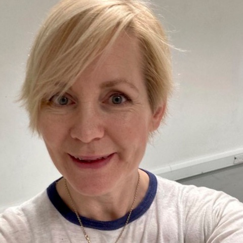 A selfie of Polly Wiseman smiling - they have short blonde hair and wear a white tshirt