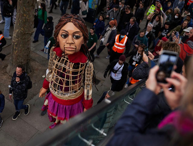 The Little Amal puppet on the Southbank looking up at the camera