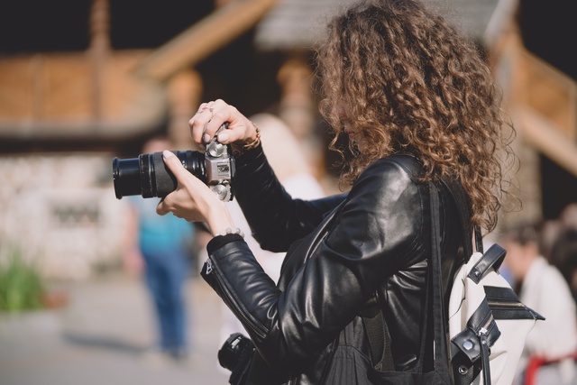 A woman takes a photo on a street