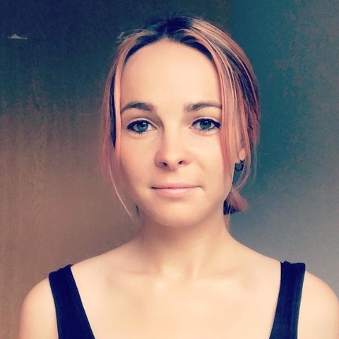 Headshot of Giverny Masso, she wears a black vest top and has pink hair