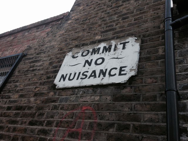A sign on a wall reading 'commit no nuisnance'