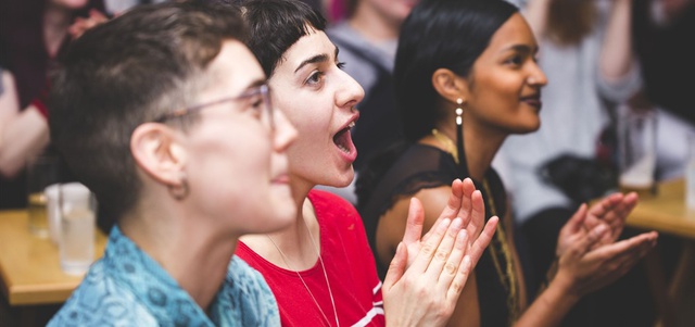 Three people watching something off camera, cheering and applauding