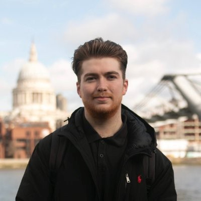 Headshot of a man wearing a black coat with a backdrop of Millennium Bridge and St Paul's cathedral