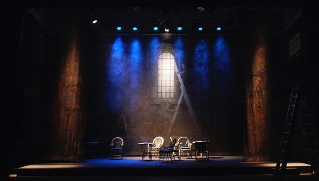 Theatre set, spotlights point down through haze to some empty seats on a stage